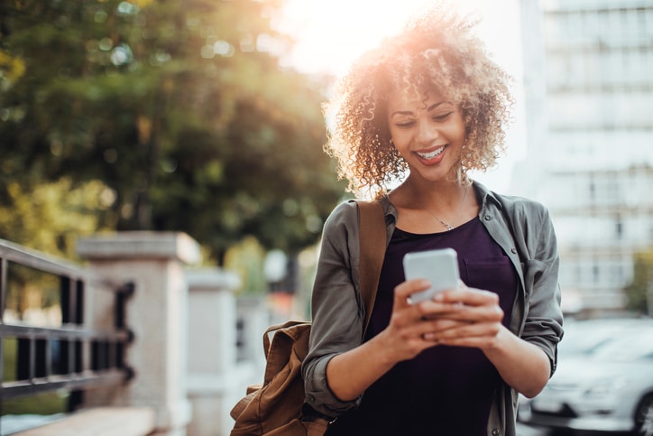Picture of a young smiling woman using a phone